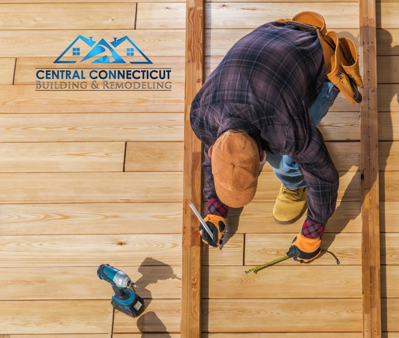 Deck Build in Newington Overhead view of a deck builder marking measurements on freshly installed wood decking boards, wearing work gloves and a tool belt — Central Connecticut Building & Remodeling on site in Newington, CT.